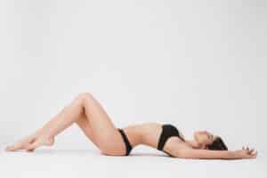 Woman with contours improved by liposuction reclines on the ground.