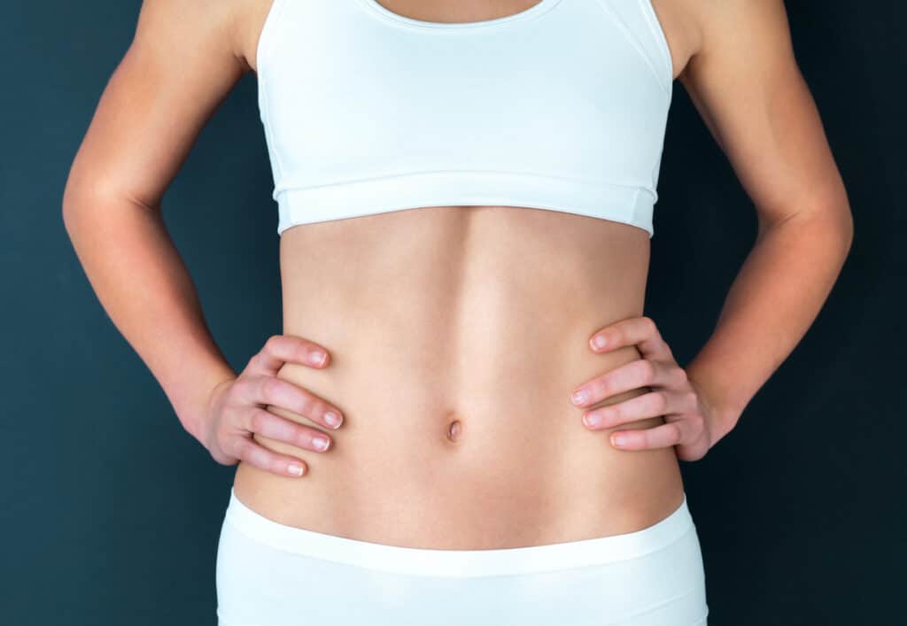 Woman showing a smooth, toned stomach after a mommy makeover.