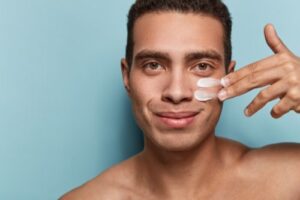man with healthy skin applies cream for anti wrinkle